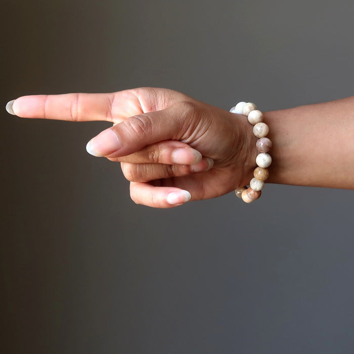 woman's hand pointing wearing yellow peach moonstone round stretch bracelet