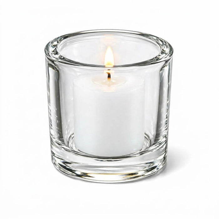 Lit white votive candle in clear glass holder on white background