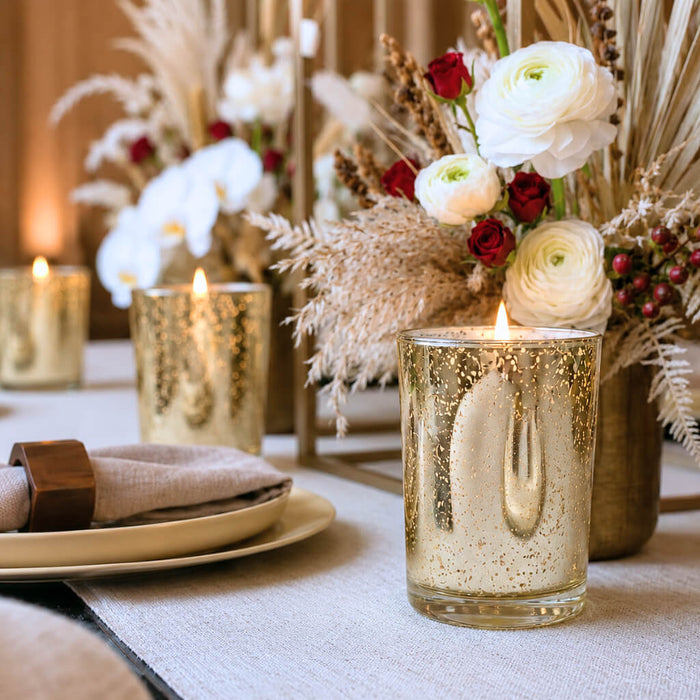 An elegant event tablescape featuring a lit candle inside a Metallic Gold Mercury Votive Holder