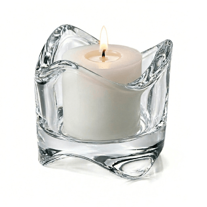 Clear glass candle holder with a white candle on a white background