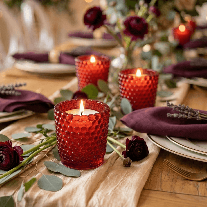Red hobnail votive holders with candles on rustic decorated dinner table