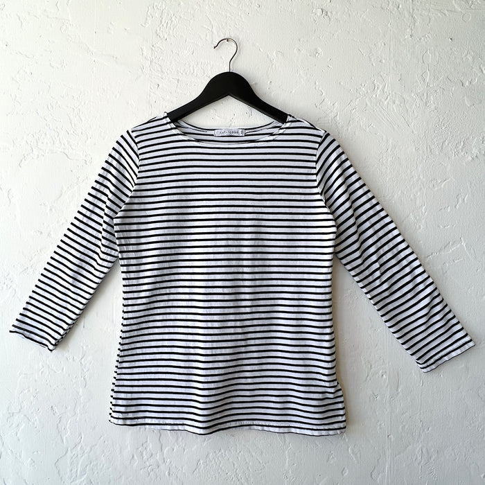 Black and white striped long-sleeve shirt on a hanger against a white wall