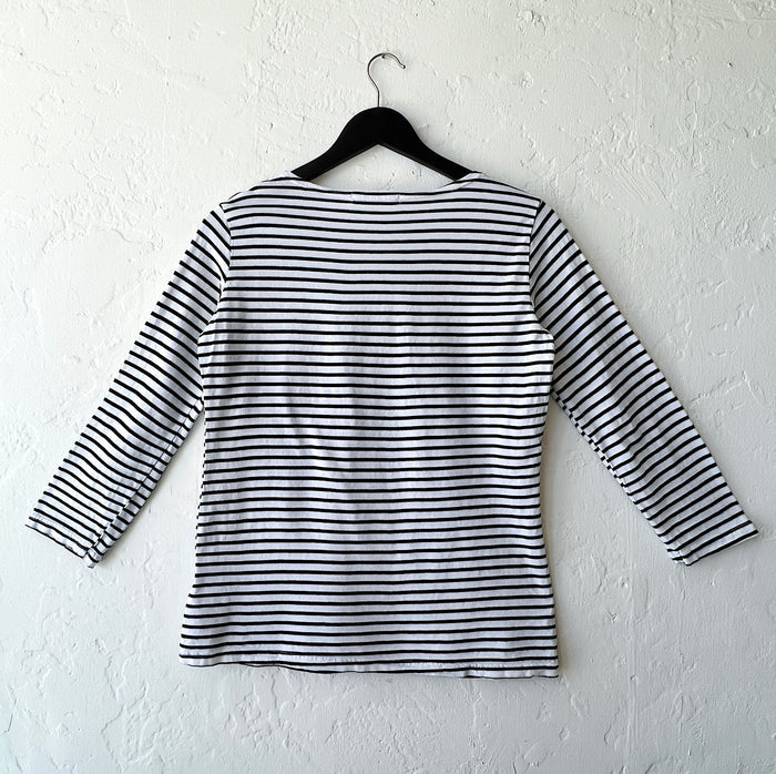 Black and white striped shirt on a hanger against a white wall as viewed from the back