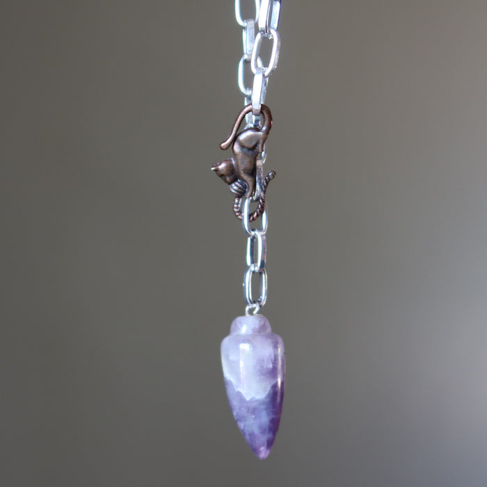 Necklace with a purple amethyst pendant and cat figure on a blurred background