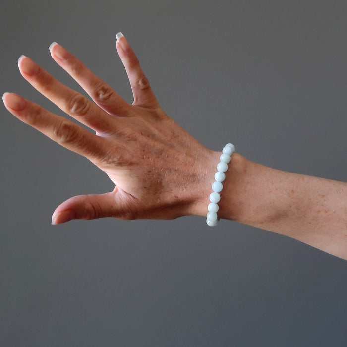 female hand modeling round blue-green aquamarine beaded stretch bracelet