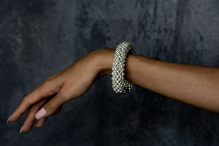 Handcrafted modular bracelet cuff from syntethic japanese pearl on wrist of woman in dark blue background