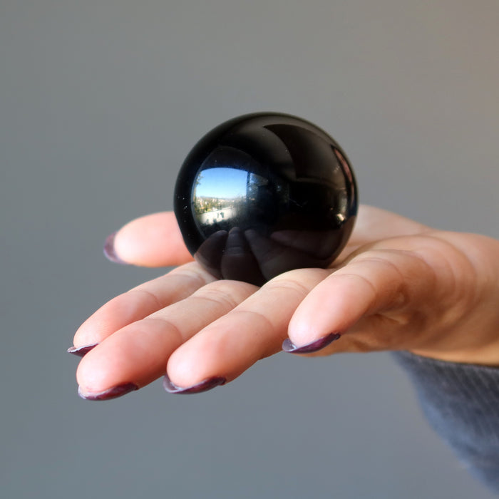 hand holding black obsidian sphere