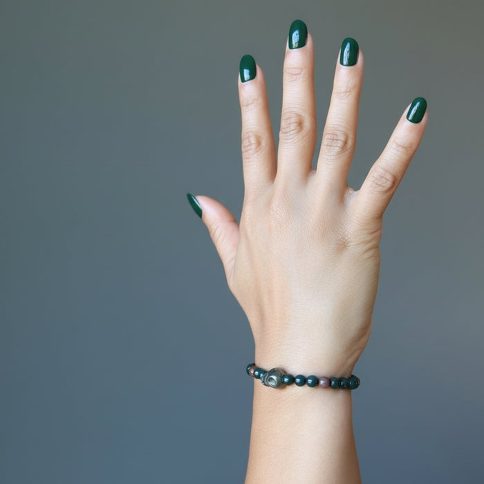 female hand wearing pyrite skull and round bloodstone beaded stretch bracelet