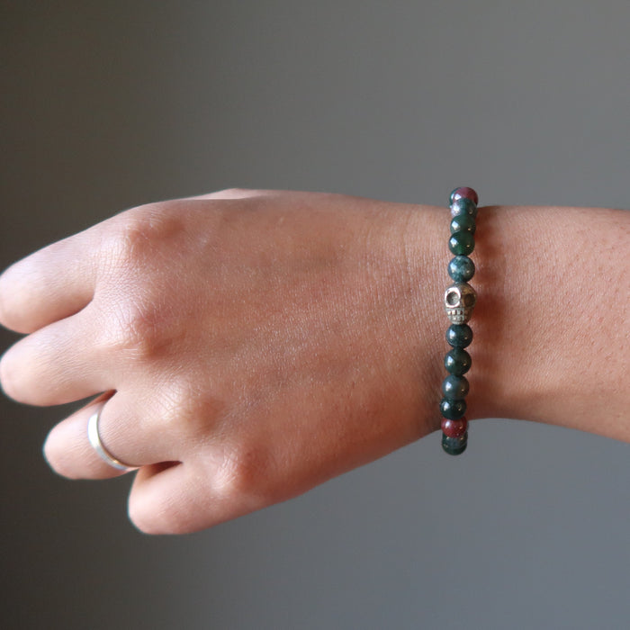 female hand wearing pyrite skull and round bloodstone beaded stretch bracelet