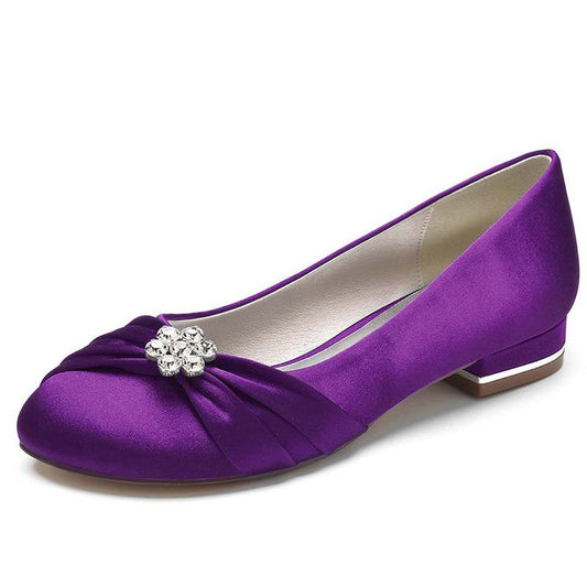 Purple shoe with a bow and crystal embellishment on a white background