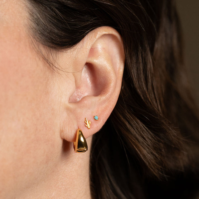 A close up of a person's ear wearing the two sets of earrings with a thick gold hoop earring