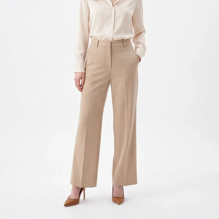 A woman modeling a light beige satin button-down shirt and matching beige wide-leg trousers, paired with brown pointed-toe heels, against a plain white studio background.