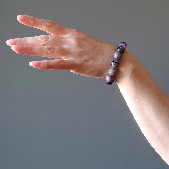 female hand modeling purple charoite stretch bracelet