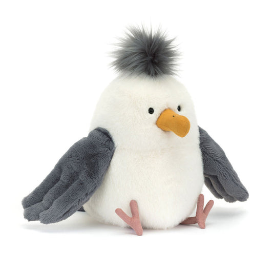 Jellycat Chip Seagull plush toy with a round white body, fluffy grey pom-pom crest, yellow beak, grey wings spread wide, and pink webbed feet, facing slightly right on a white background