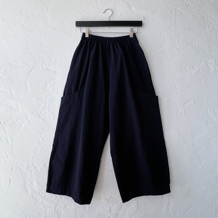 Black wide-leg pants hanging on a white wall