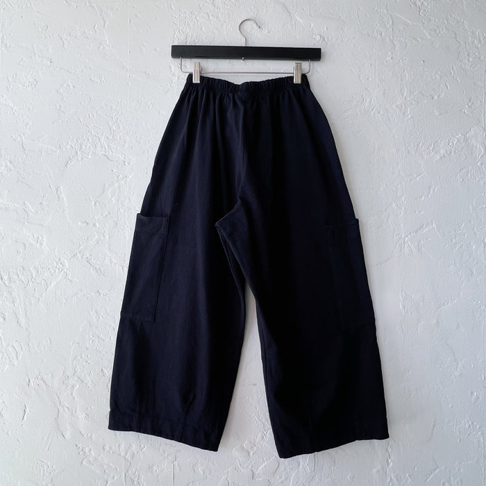 Black wide-leg pants hanging on a hanger against a white wall