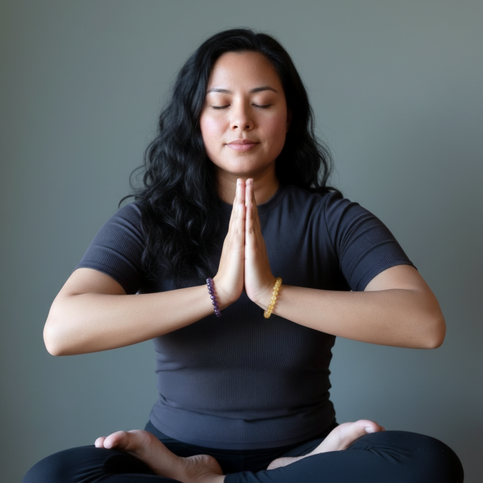 Woman in a yoga pose with hands pressed together against a gray background
