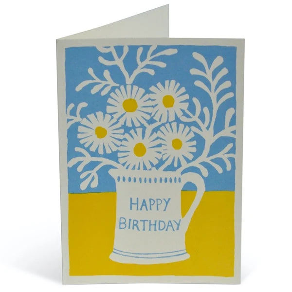Greeting card with a white mug of flowers and 'Happy Birthday' text on a blue and yellow background