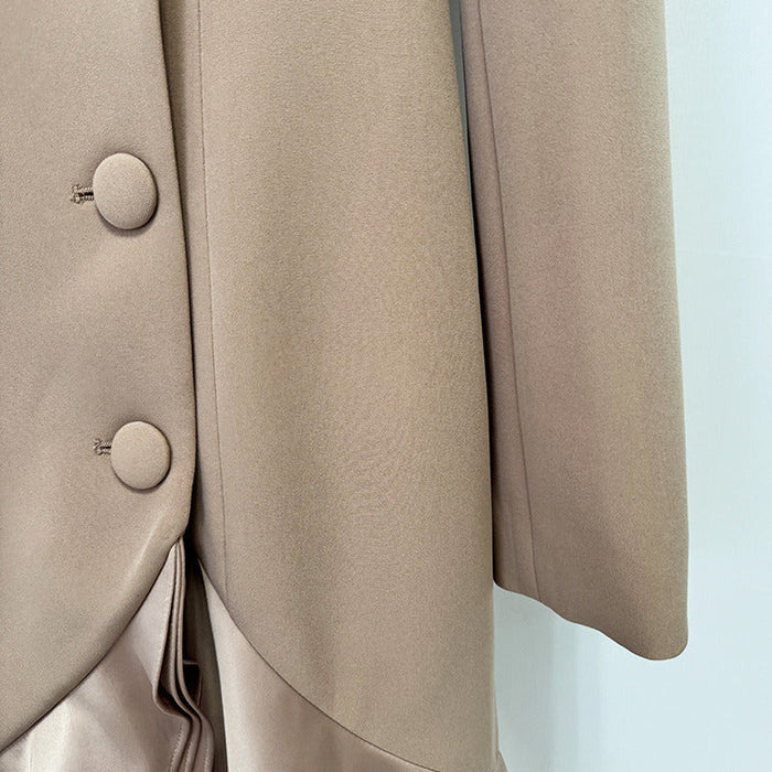 Close-up of a beige tailored jacket or blazer with large round buttons and a smooth satin-like draped fabric panel in a matching light taupe color.