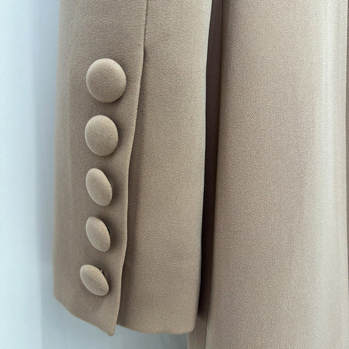 Close-up of a beige or taupe fabric garment detail showing a sleeve or panel with five large round buttons on the left side and smooth matching fabric on the right.