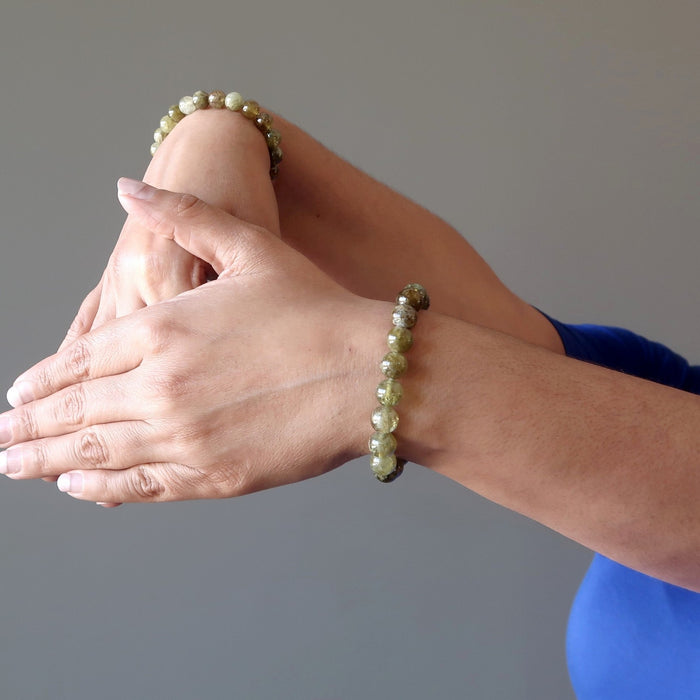 two hands posing wearing green garnet bracelets