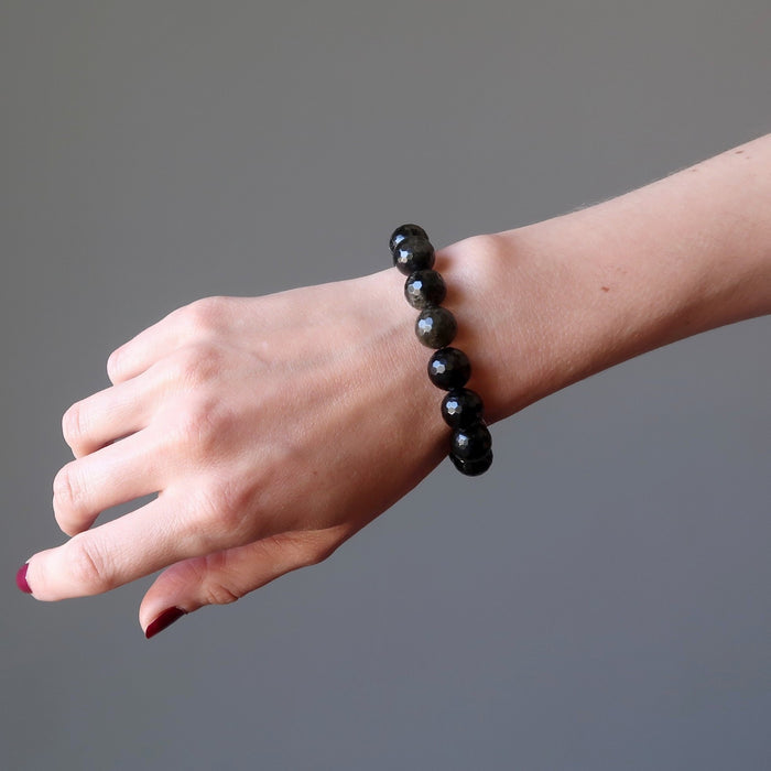 female hand modeling faceted gold sheen obsidian bracelet