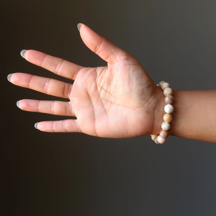 woman's hand wearing yellow peach moonstone round stretch bracelet