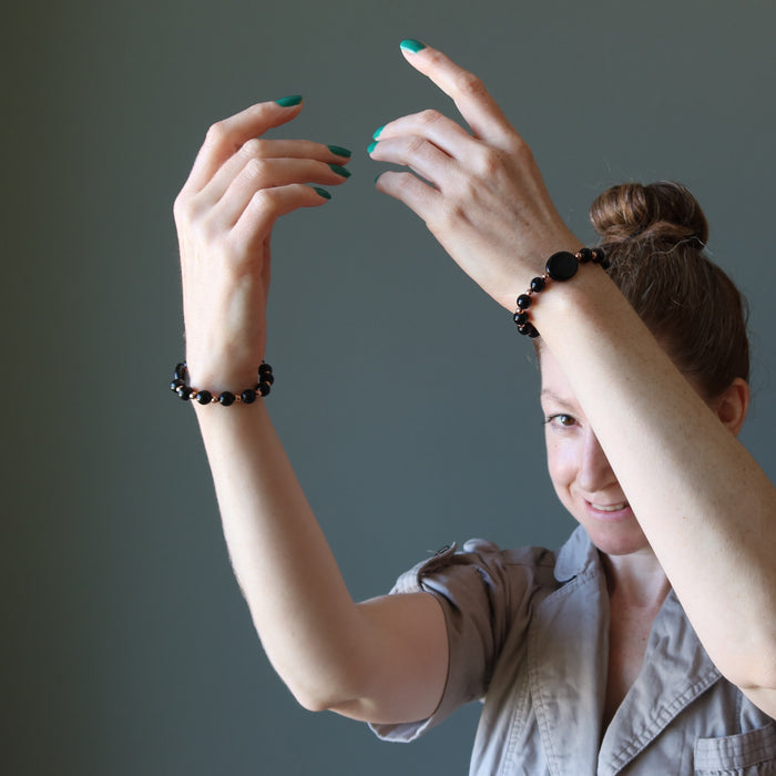 female model with hands raised wearing black jet stone and copper beaded bracelets