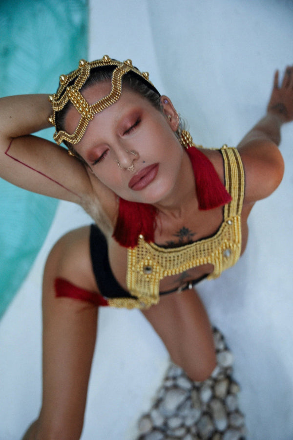 woman sitting beside pool with white tile facing camera with khutulun headband and artemisia mesh top in gold by object and dawn