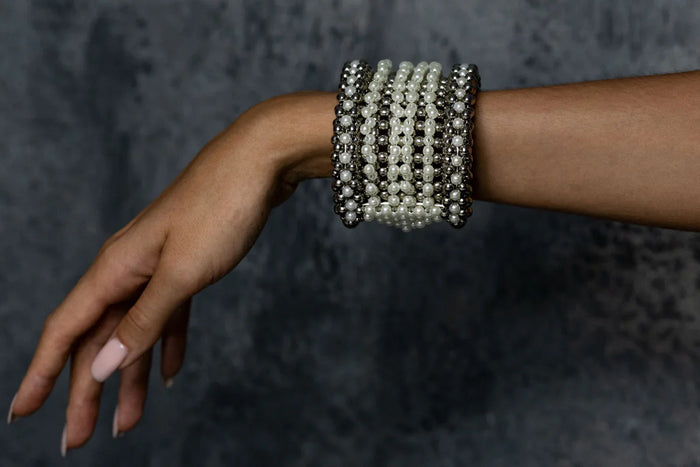 Handcrafted modular bracelet cuff from syntethic japanese pearl on wrist of woman in dark blue background