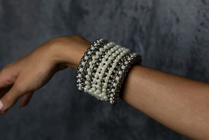 Handcrafted modular bracelet cuff from syntethic japanese pearl on wrist of woman in grey background