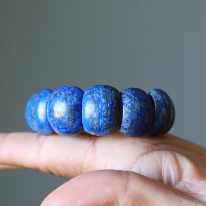 Blue stone Lapis bracelet on a hand against a gray background