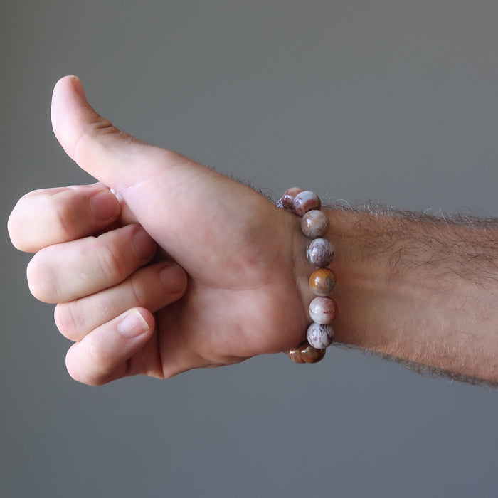 colorful red swirl Pietersite bracelet on a male hand model as he does a thumbs up