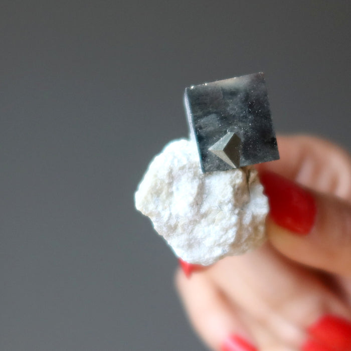 hand holding pyrite cube on white matrix