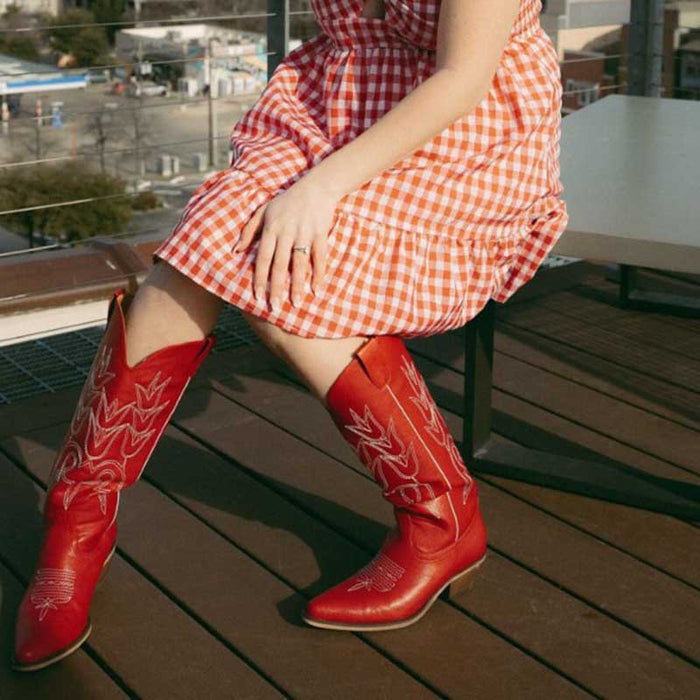 red chunky cowgirl boots for women paired with a gingham dress on a sunny patio