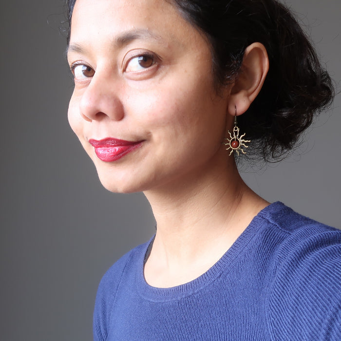 woman wearing red jasper stone earrings with sun-shaped designs