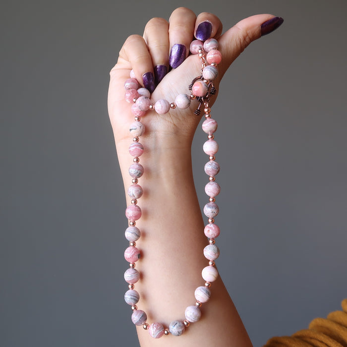 hand holding rhodochrosite necklace