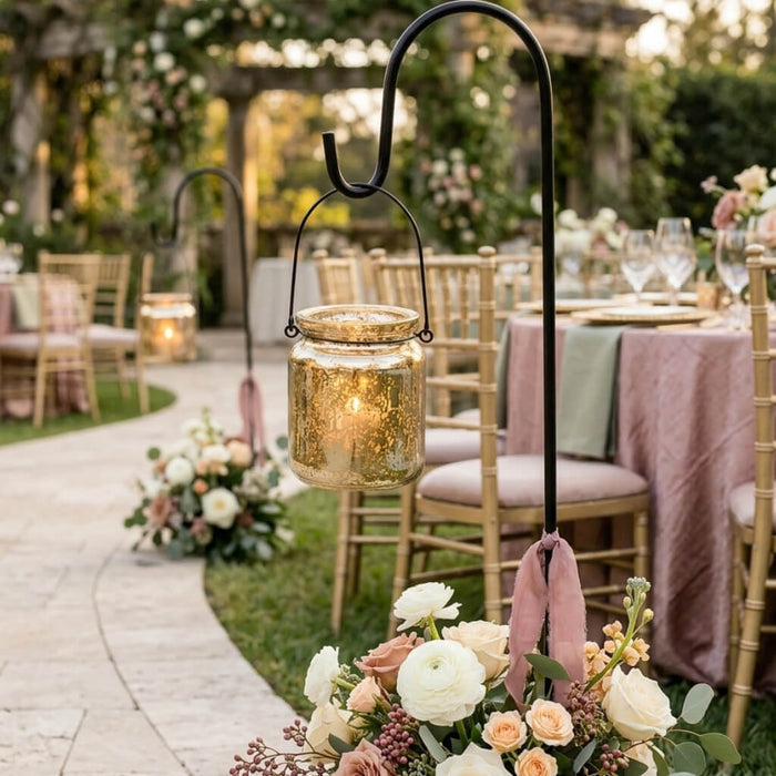 Gold mercury glass hanging holders lining a garden wedding aisle with floral arrangements and ribbons
