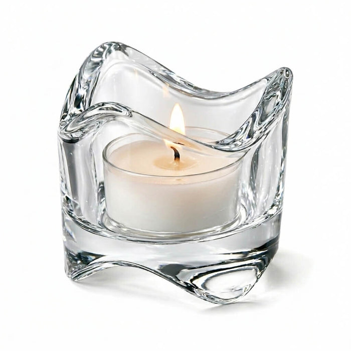 Clear glass candle holder with a lit white candle on a white background