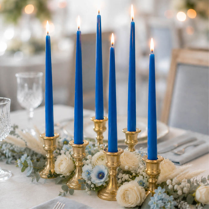 Lit blue taper candles with gold candlesticks and white flowers