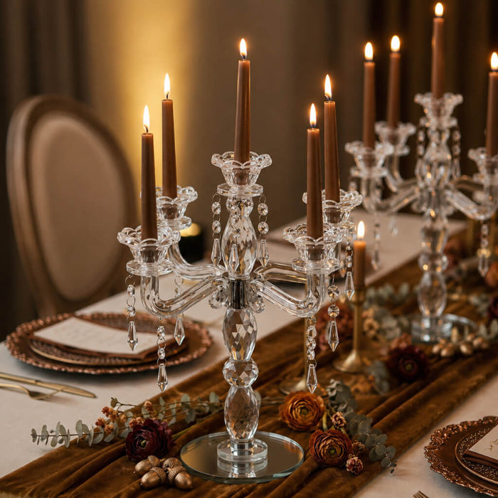 Lit brown candles in crystal holders on a warm, formal tablescape