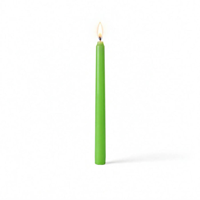 Single green taper candle with flame on white surface