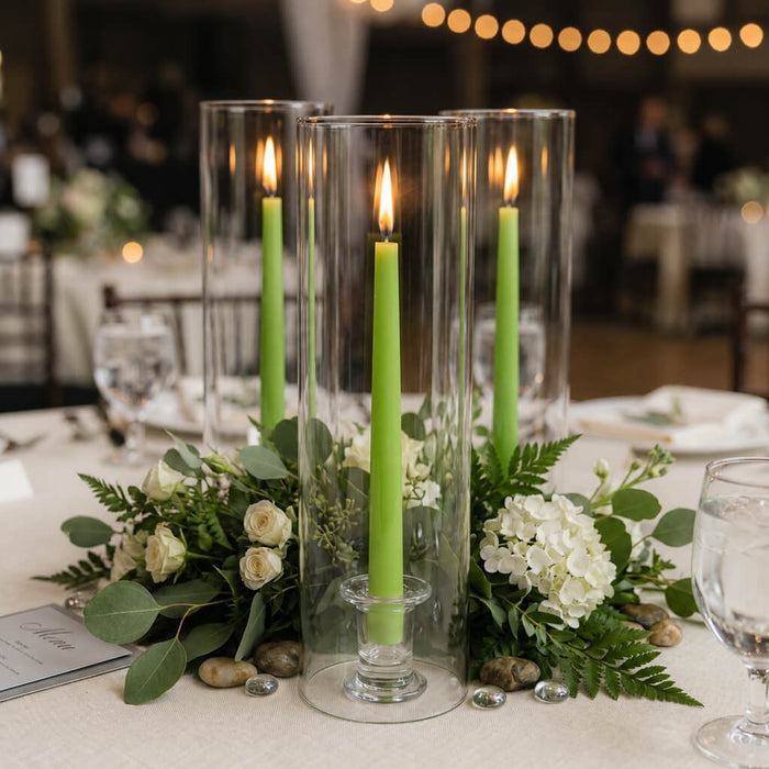 Green taper candles in clear glass holders with floral arrangement