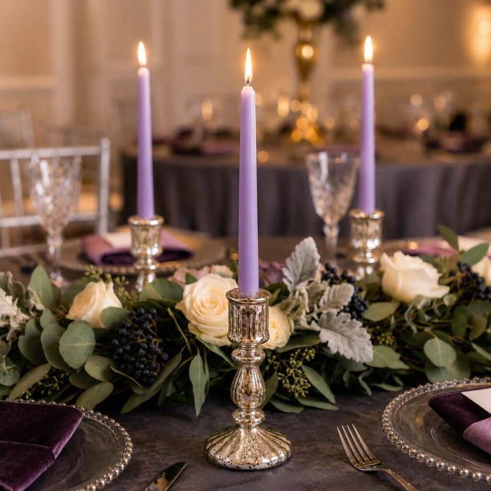 Lavender taper candles with greenery and white roses on dining table