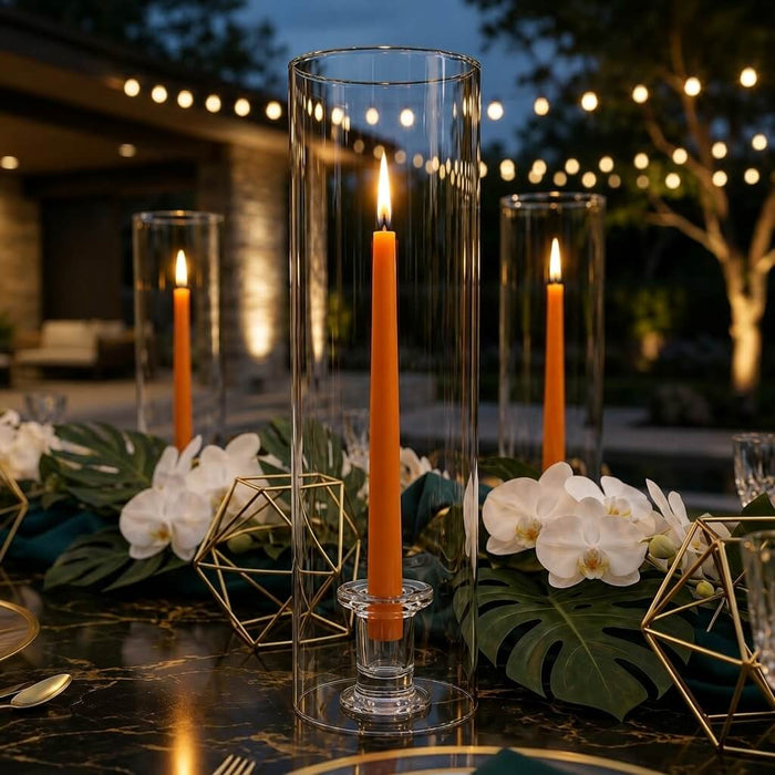 Outdoor evening tablescape with orange taper candles in glass cylinder vases
