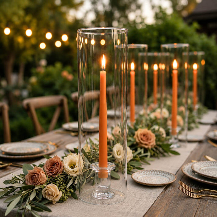 Orange taper candles in glass cylinder vases on a romantic outdoor tablescape