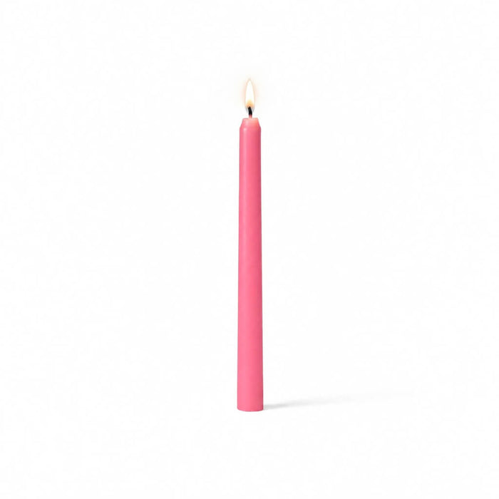 Single pink taper candle with flame on white backdrop