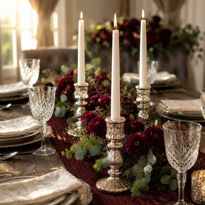 Candlelit dining table with white candles and burgundy flower garland