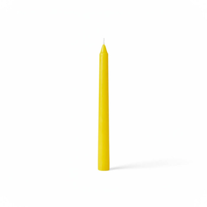 Single yellow taper candle on white backdrop