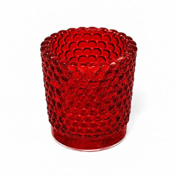 Red hobnail glass votive holder on white backdrop